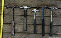 Group of five claw hammers with measuring tape for scale