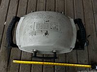 Top view showing Weber logo, lid condition, size reference with measuring tape