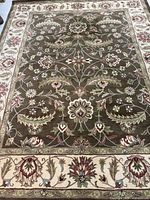 Full view of rectangular olive green floral rug with beige border