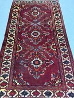 Full view of Persian Ferdos Mashad rug showing red field and borders