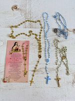 All four rosaries and prayer card laid out