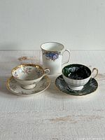 three cups with two saucers showing patterns and overall condition