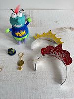 Group shot showing plush doll, two headbands, keychain and mini hat