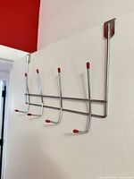 Rack installed over door showing hooks with red tips