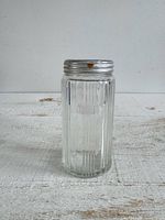 Full view of clear ribbed glass jar with metal lid
