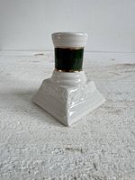 Front view of ceramic candlestick holder showing white base, green band, gold accents