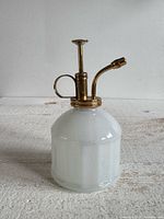 Front view of white glass body and brass pump mister