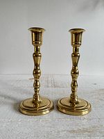 Full view of both brass-plated candlestick holders standing upright