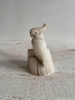 Front view of carved stone parrot on base