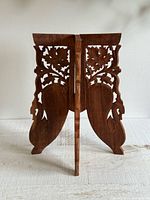 front view of folded three-leg carved wood base