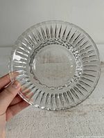 Top view of clear glass ashtray showing patterned rim and slots