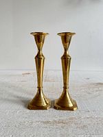 Front view of both brass candlestick holders standing side-by-side