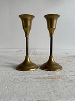 Full view of both brass candlestick holders standing side by side