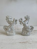 Front view pair white lusterware rearing horse figurines on wooden surface