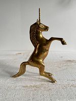 Left side view of brass unicorn standing on hind legs
