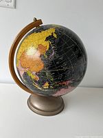 Full view of globe on stand, showing wood meridian and metal base