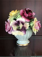 Front view of multicolor bone china flower arrangement in white ribbed vase with gold foot