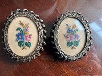 Front view of both oval frames showing petitpoint inserts and ornate brass-tone borders