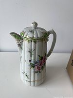 Front view showing floral design, spout, lid, finial