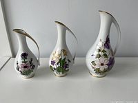 Front view of three porcelain floral vases/pitchers