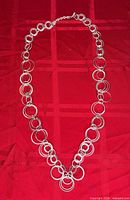 Full view of silver circular-link necklace laid flat showing entire length and clasp