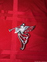 Front view of silver tone angel brooch on red background