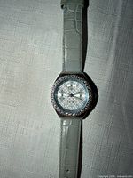 Front view of DMQ watch showing crystal bezel, dial, and strap colour