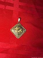 Front view of square damascene pendant on red background