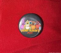 Front view of Freddy Fazbear's Pizza button showing characters and text