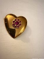 Front view of gold-tone heart brooch showing pink crystal flower detail