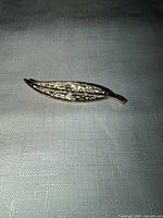 front view of gold tone leaf brooch showing rhinestones