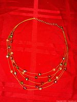 Full view of necklace showing four wire strands with multi-colour faceted beads and clasp