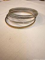 Stacked view of five bangles showing textures and finishes