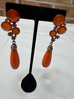 Front view of both orange stone drop earrings on stand