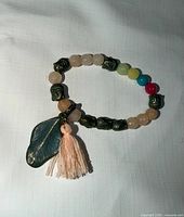Bracelet laid flat showing full design, beads, leaf charm and tassel