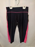 Front view of black cropped leggings with pink side stripe