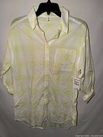 Front view of BP yellow and white plaid button-down shirt showing collar, buttons, chest pocket, sleeves, and attached price tag