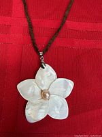 Close view of shell flower pendant on brown cord