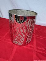 Front view of cylindrical silver metal candle holder showing etched tree pattern