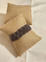 Full view of silver-tone braided cuff bracelet on display pillow