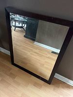 Frontal view of rectangular mirror with dark wood frame
