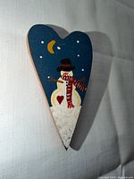 Front view of wooden heart brooch showing painted snowman motif