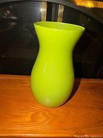 Full view of lime green vase on wooden surface
