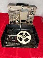 Rear view of Argus M750 projector showing speaker grille, control panel, power cord, tray and take-up reel