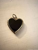 Front view of heart-shaped locket showing black enamel face and bail