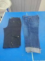 Blue denim and black cargo Capri pants laid side by side