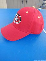 Left side view of red 49ers cap showing logo and brim