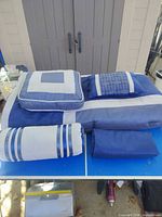 Comforter, bed skirt and three pillows arranged on table