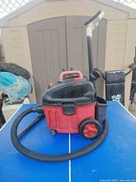 Vacuum with hose and attachments shown on table