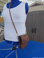 Full view of brown crossbody purse on mannequin showing size and adjustable strap